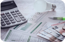 Mesa com uma calculadora, dinheiro, faturas e lâmpada